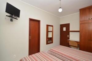 een slaapkamer met een bed, een bureau en een televisie bij Villas Boas Hotel in Campinas