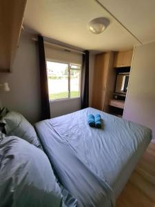 a bedroom with a bed with two blue slippers on it at Mobil home 5 personnes proche Samoëns et Morillon in Verchaix +2 photos