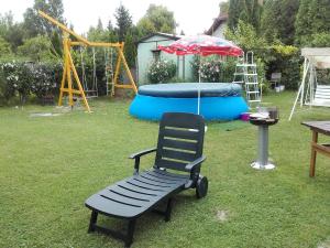 un parque infantil con banco y sombrilla en un patio en János Nyaraló en Balatonmáriafürdő