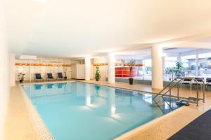 a large indoor swimming pool with blue water at Bodensee Loft - 116 m² Traumwohnung in Uhldingen-Mühlhofen