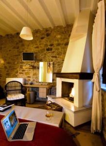 a living room with a fireplace and a laptop on a table at Guesthouse Theonimfi in Dimitsana