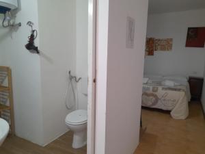 a bathroom with a toilet and a bed at La Locanda Ta Nonna Tuta in Parabita