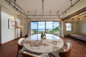 a room with a table and chairs and a large window at クリスタル別荘南城 in Nanjo