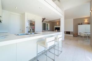 una cucina con mobili bianchi e un bancone con sgabelli di Villa Rucchetta a Casa Linari