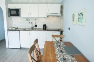 a kitchen with white cabinets and a wooden table and chairs at Apartment Las Americas in Playa de las Americas
