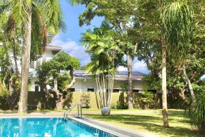 a swimming pool in front of a building with palm trees at Tropical Terrace Negombo in Negombo