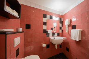 パリにあるWalled off Hotel Parisの赤いタイル張りのバスルーム(洗面台、トイレ付)