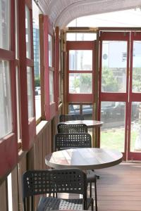 eine Reihe von Tischen und Stühlen in einem Zimmer mit Fenstern in der Unterkunft Capsule Inn Gangneung in Kangmun + 79 Fotos