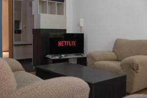 a living room with a tv and two chairs and a coffee table at APT Near Millenium Cross,Clinical Center Mother Teresa, City-Center,Free Parking in Skopje