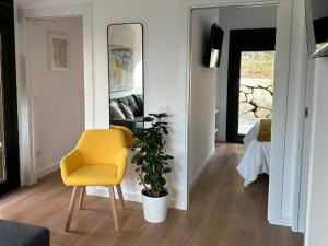a living room with a yellow chair and a plant at Resort Natur O Grove in O Grove