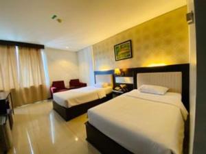 a hotel room with two beds and a chair at Zahra Syariah Hotel Kendari in Pipulu +105 photos