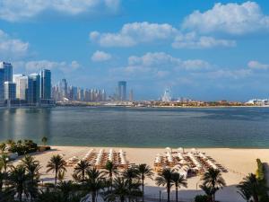 a beach with chairs and palm trees and a city at Fairmont The Palm in Dubai