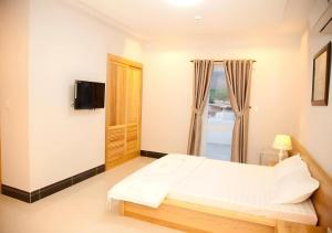 a bedroom with a bed and a tv and a window at Seaview Long Hai Hotel in Long Hai
