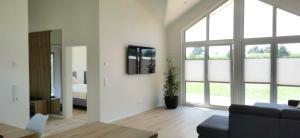 a living room with a couch and a bed and windows at Ferienhaus Elbdeichblick 1 in Haselau
