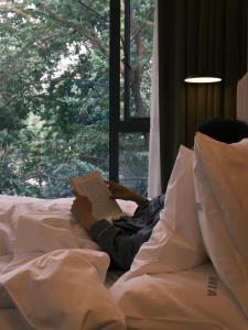 a person laying on a bed reading a book at Ayata Hotel in Chengdu