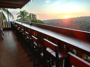 a bar with chairs and the sunset in the background at Senaru Lodge in Senaru