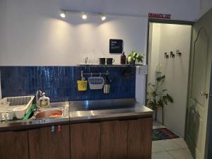 Dramatic Exit Bangkok - Cozy loft style near Suvarnabhumi Airport في بانكوك: مطبخ مع حوض والجدار الأزرق البلاط