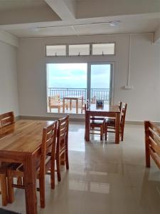 a dining room with a table and chairs and a large window at Fanai Inn in Āīzawl