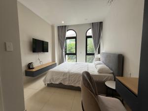 a bedroom with a bed and a tv and windows at Three women in Phu Quoc