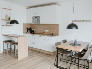 a kitchen with white cabinets and a table and chairs at Haus NordQuartier in Norderney