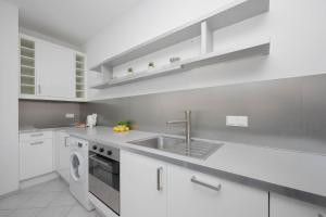a white kitchen with a sink and a dishwasher at Spacious and Bright Apartment with Parking in the City Center by Noclegi Renters in Warsaw