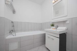 a white bathroom with a sink and a bath tub at Spacious and Bright Apartment with Parking in the City Center by Noclegi Renters in Warsaw +21 photos