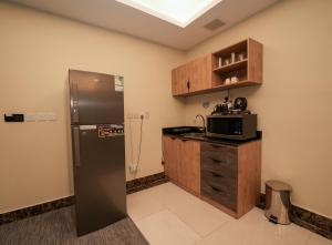a kitchen with a refrigerator and a microwave at بنزرت للشقق الفندقية in Al Hofuf