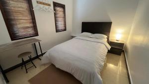 a bedroom with a large white bed and a desk at Schonen House by Ruby Living in Yogyakarta