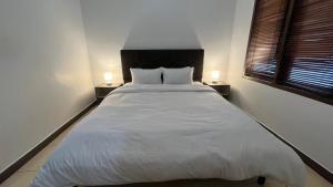 a large white bed in a room with two lamps at Schonen House by Ruby Living in Yogyakarta +4 photos