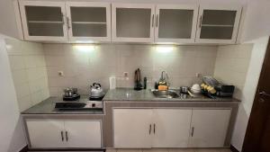 a kitchen with white cabinets and a sink at Schonen House by Ruby Living in Yogyakarta