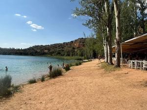 a beach with people swimming in a lake at Atardecer dorado in Ruidera