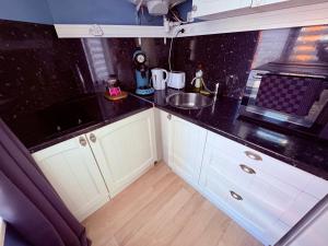 a kitchen with white cabinets and a black counter top at Pause Confort Studio idéal centre ville in Gravelines +6 photos
