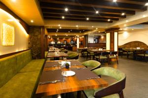 a restaurant with wooden tables and green chairs at Sumitel Queens Yard in Darjeeling
