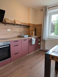 a kitchen with pink cabinets and a sink at Ferienwohnung am Eifelsteig in Üxheim