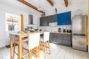 una cocina con armarios azules y una mesa y sillas de madera. en Entre Terre et Sel - Centre Bouin - Wifi, en Bouin