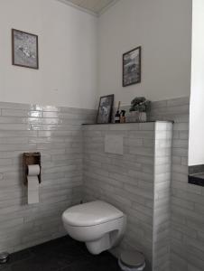 a white bathroom with a toilet and some pictures on the wall at Ferienwohnung am Eifelsteig in Üxheim +19 photos