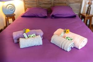 Una cama púrpura con toallas y flores. en Entre Terre et Sel - Centre Bouin - Wifi, en Bouin 8 fotos más