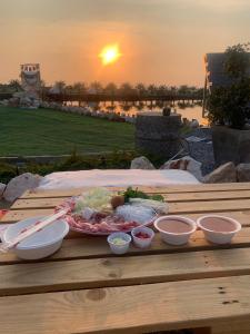 un piatto di cibo su un tavolo di legno con il tramonto di บ่อดินอินไซด์เอาท์BhorDin InSideOut 