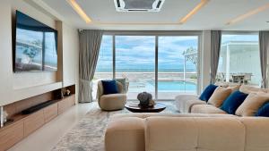 a living room with a large couch and a tv at Topseavilla Poolmoon in Ban Bo Yai