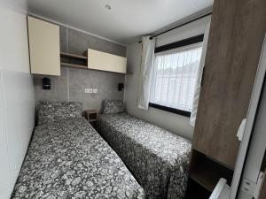 Dos camas en una habitación pequeña con ventana. en Mobil-home Bora camping les Embruns, en Lège-Cap-Ferret
