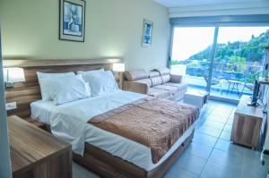 a bedroom with a bed and a couch and a window at Hotel & Beach Club Mediterraneo Liman in Ulcinj