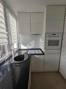 a white kitchen with a sink and a stove at Apartament Klonowa in Kraśnik +5 photos