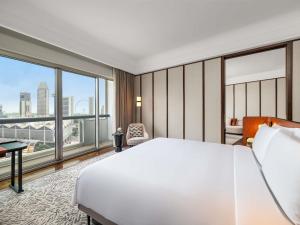 a bedroom with a large white bed and large windows at Fairmont Singapore in Singapore