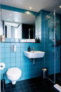 a blue tiled bathroom with a toilet and a sink at The Social Hub Delft Extended Stay in Delft