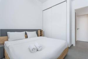 a bedroom with a large white bed with towels on it at Sketch - Innovative 1-BR Apt by Convivium IX in Monot in Sodeco