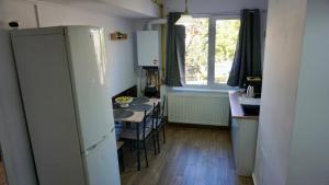 a kitchen with a refrigerator and a table with chairs at Chic and sunny downtown apartment in Braşov