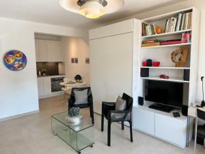 a living room with a tv and a table with chairs at Palme 004 by Fewotessin in Locarno