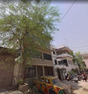 un coche aparcado frente a un edificio con un árbol en Annapoorna Niwas, en Patna