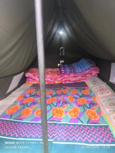 a bed in a tent with a colorful blanket at Trivedi Camps in Kedārnāth