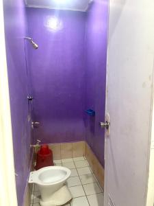 a bathroom with a toilet and a purple wall at Cherry Traveller Inn in San Jose de Buenavista